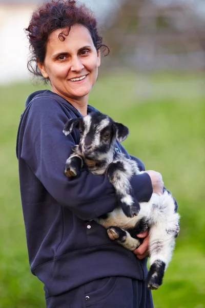 Jeune femme avec bébé chèvre en plein air — Photo
