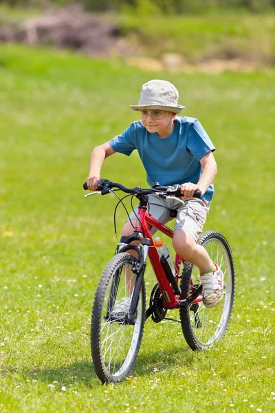 Мальчик на велосипеде по травяному полю — стоковое фото