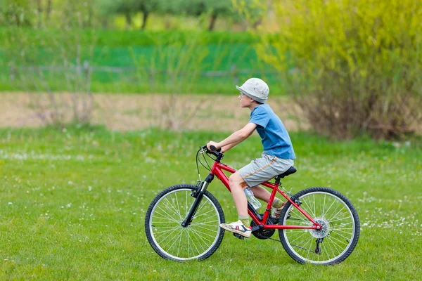 戴着帽子骑自行车的男孩 图库图片