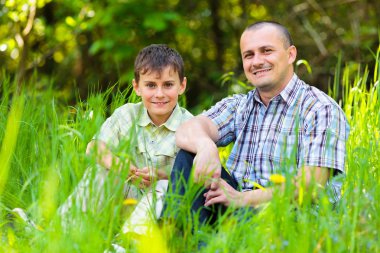 Father and son sitting in grass