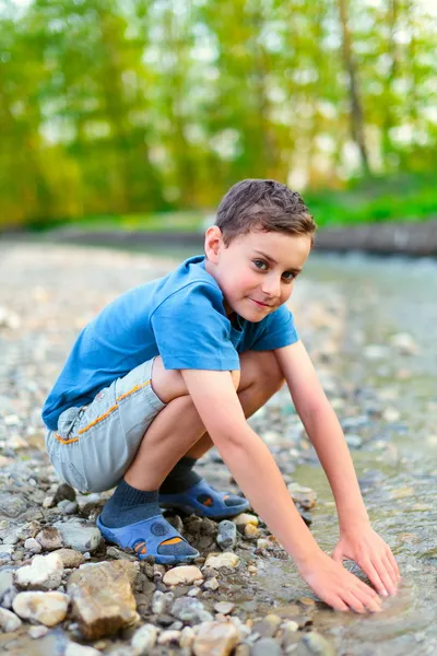 Ευτυχισμένο παιδί που παίζει στην όχθη ενός ποταμού — Φωτογραφία Αρχείου
