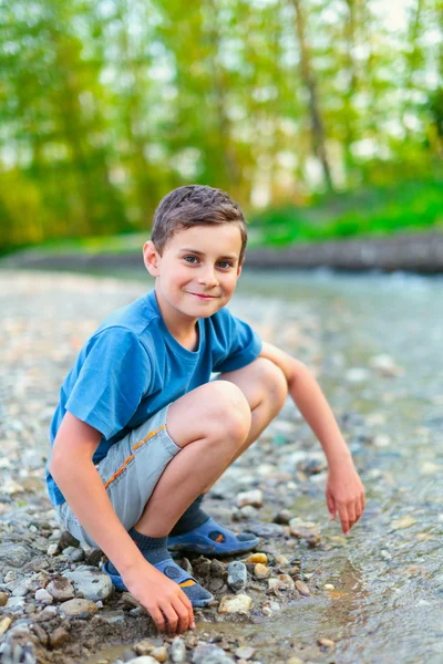 Šťastné dítě hraje na břehu řeky — Stock fotografie