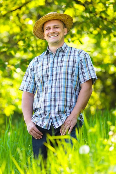 Jonge man in stro hoed buiten in een tuin — Stockfoto