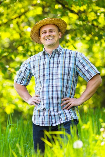 Mladý muž v slamák venkovní v zahradě — Stock fotografie