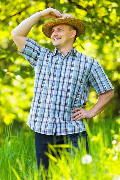 Junger Mann mit Strohhut draußen im Garten — Stockfoto