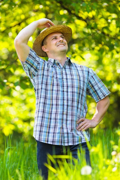Νεαρός άνδρας στο υπαίθριο ψάθινο καπέλο σε έναν κήπο — Φωτογραφία Αρχείου