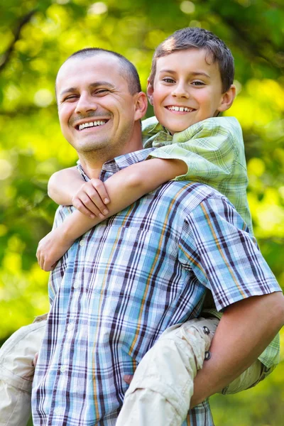 Otec nosí syna na zádech — Stock fotografie