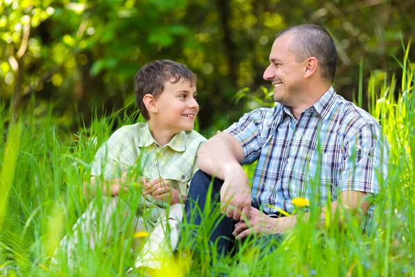 Отец и сын сидят в траве — стоковое фото