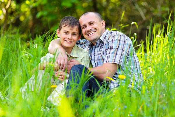 Father and son sitting in grass — Stok fotoğraf