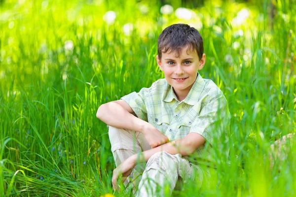 Felice ragazzo seduto in erba — Foto Stock