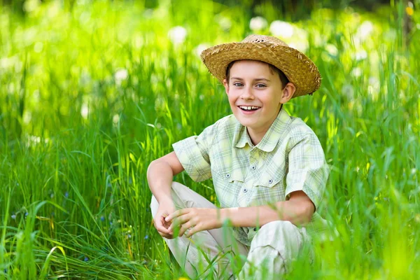 Счастливый мальчик сидит в траве — стоковое фото