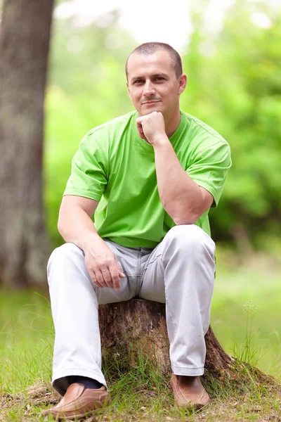 Junger Mann sitzt auf einem Baumstamm — Stockfoto