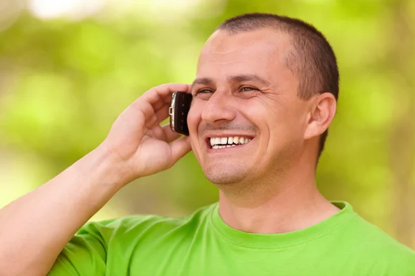 Ung man talar på mobiltelefon utomhus — Stockfoto