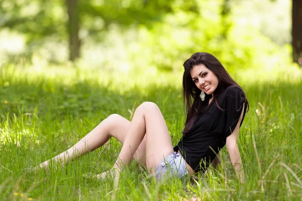 Молода жінка сидить у траві — стокове фото