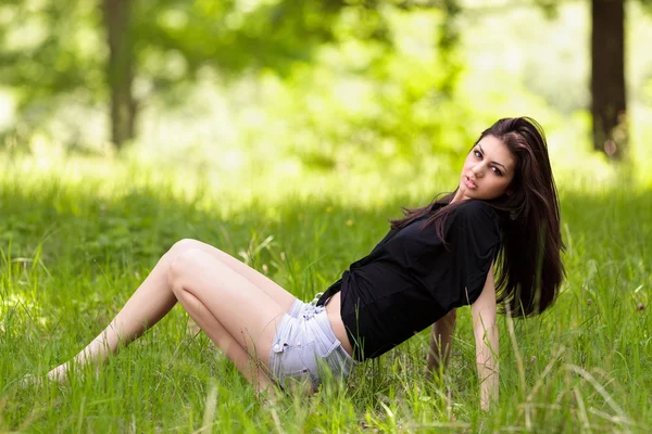 Jonge vrouw zitten in gras — Stockfoto