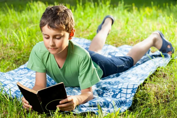 Junge liest draußen ein Buch — Stockfoto