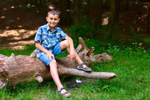 Kind sitzt im Freien auf einem Baumstamm — Stockfoto