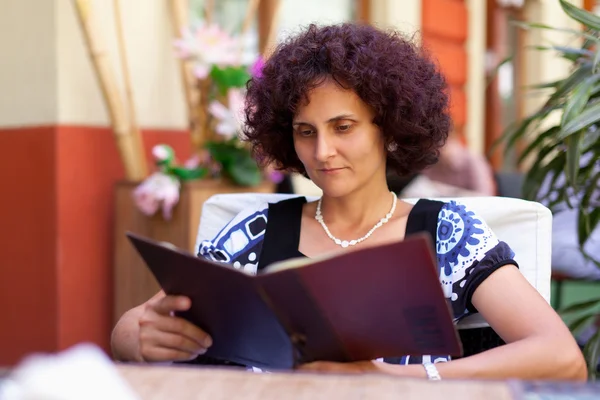 Mulher lendo livro de menu em um restaurante — Fotografia de Stock