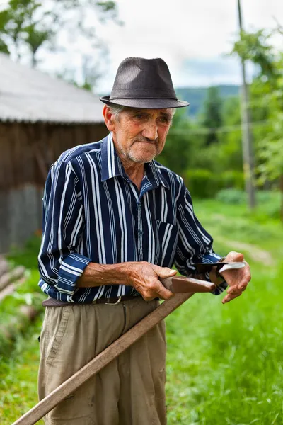 Old rural man sharpening scythe Stock Picture