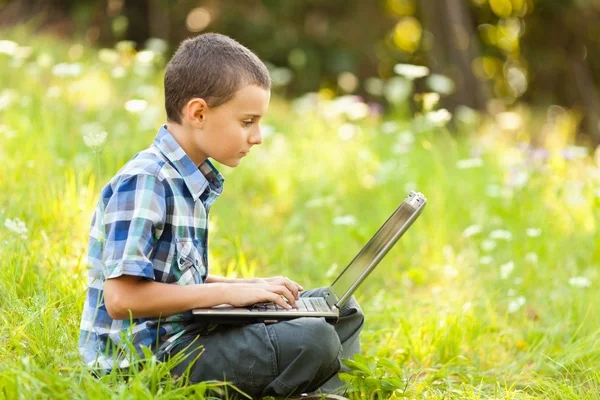 Jongen met behulp van laptop buiten — Stockfoto