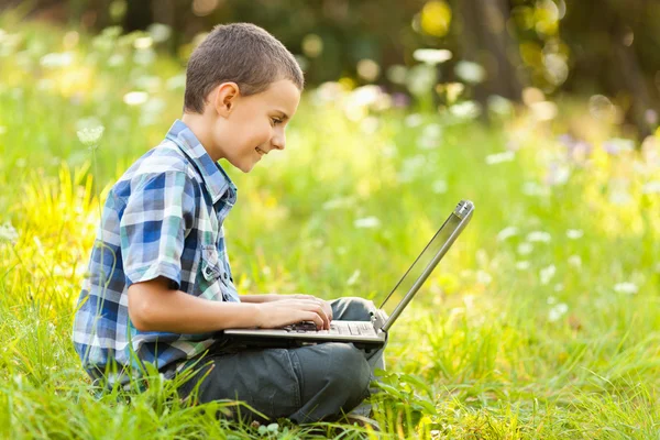 Хлопчик використовує ноутбук на відкритому повітрі — стокове фото