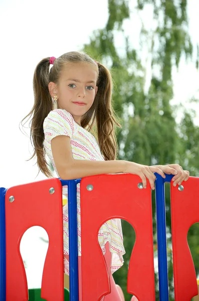 Girl standing after a red fence — Stock Photo, Image