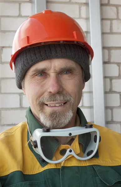 Um trabalhador idoso com óculos e um capacete de proteção — Fotografia de Stock