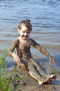 Baby girl in the mud on the river clipart