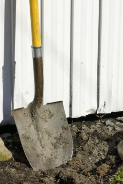 Shovel in earth against garden shed clipart