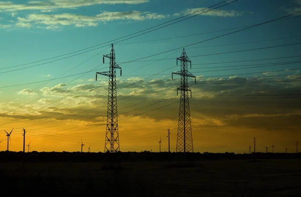 Pilares de eletricidade e turbinas eólicas no pôr do sol — Fotografia de Stock