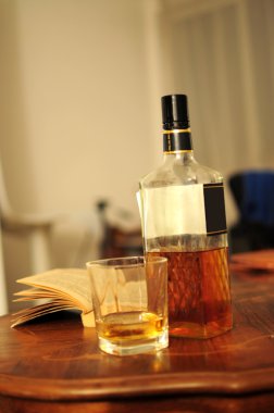 Glass of whiskey, bottle and opened book clipart