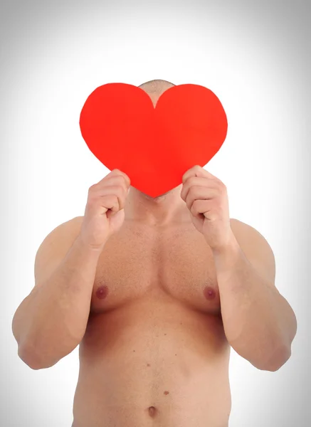 Young muscular man holding heart on his face — Stock Photo, Image