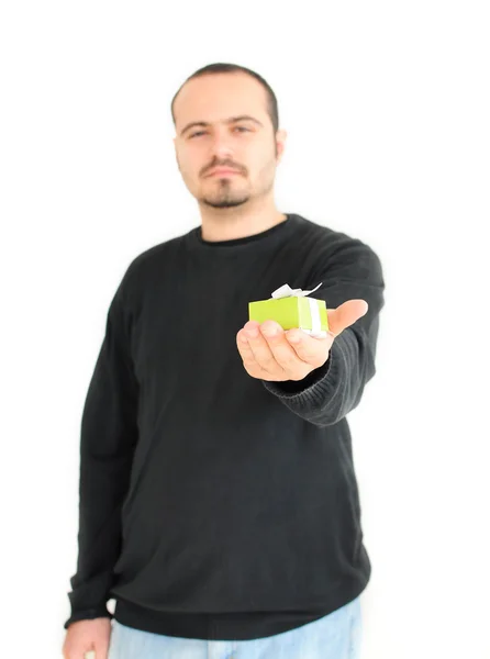 Young man holding small gift(focus on gift) — Stock Photo, Image