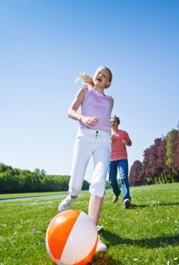 Children playing ball in a park clipart