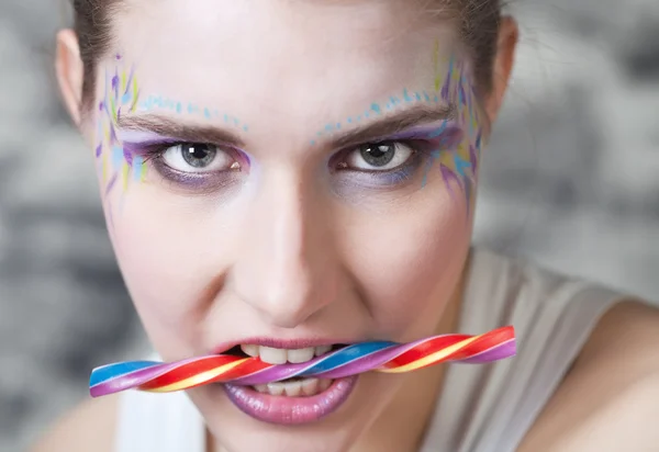 Young woman holding candy in her teeth — Stock Photo, Image