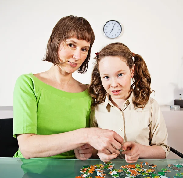 Dospívající dívka sestavování puzzle s matkou — Stock fotografie