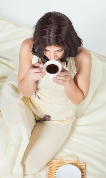Genç kadın kahve içme yatakta oturuyordu — Stok fotoğraf