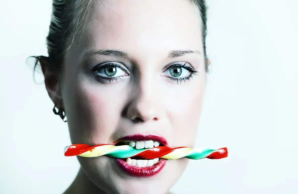 Jovem mulher segurando doces em seus dentes — Fotografia de Stock