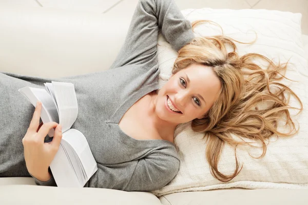 Happy young woman lying with book — Stock Photo, Image