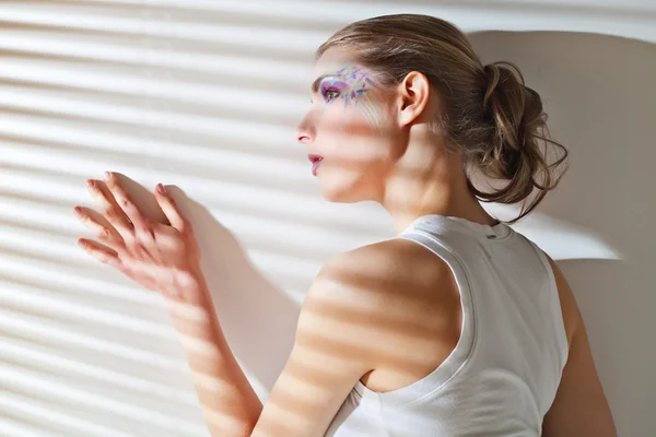 Woman standing by the window with blinds — Stock Photo, Image