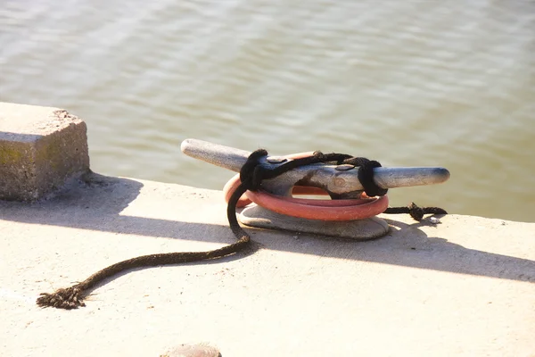 Vieille corde effilochée attachée à une cale sur le bord de la jetée de béton — Photo