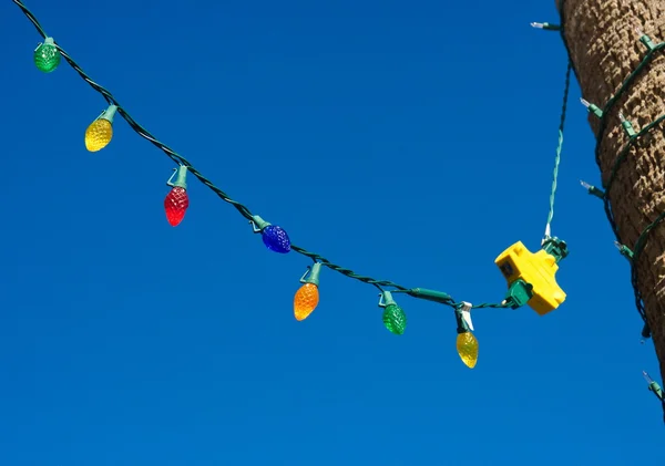 Lumières de Noël colorées suspendues à travers le ciel bleu — Photo