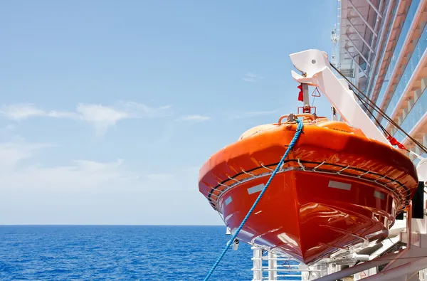 Bateau de sauvetage orange suspendu au harnais au-dessus de la mer bleue profonde — Photo
