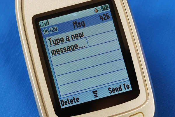 블루에 고립 된 휴대 전화에 새로운 sms 텍스트 메시지를 입력 — 스톡 사진