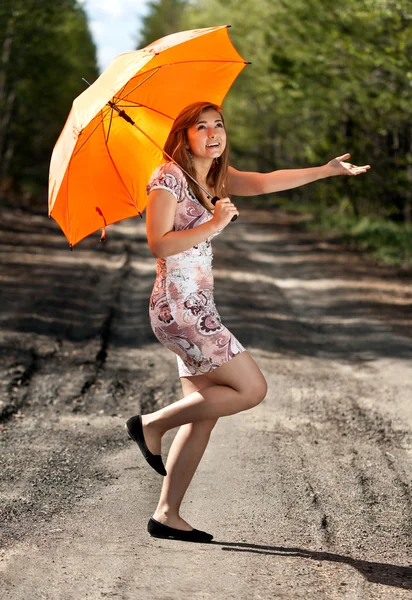 Gyönyörű lány, egy narancs esernyő — Stock Fotó