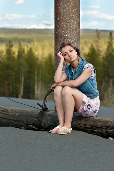 Triest meisje, zittend op een logboek — Stockfoto
