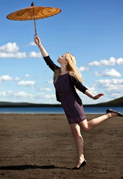 Szőke lány egy keleti ernyőt, az ég és a ruhát hegyi — Stock Fotó