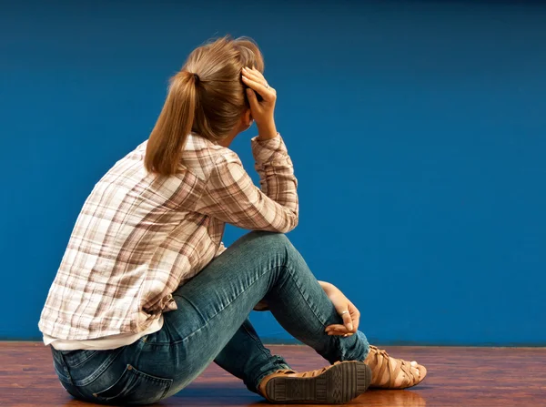 Beledigd door een meisje, zittend op de vloer — Stockfoto