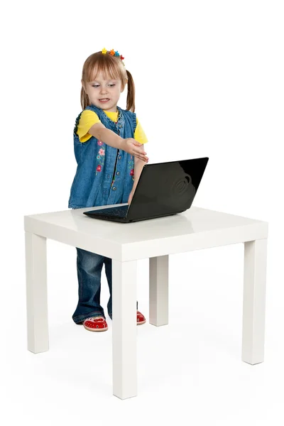 Little girl with a laptop at a table — Stock Photo, Image