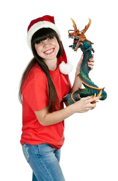 Menina em chapéu de Santa com um dragão de madeira decorativo — Fotografia de Stock